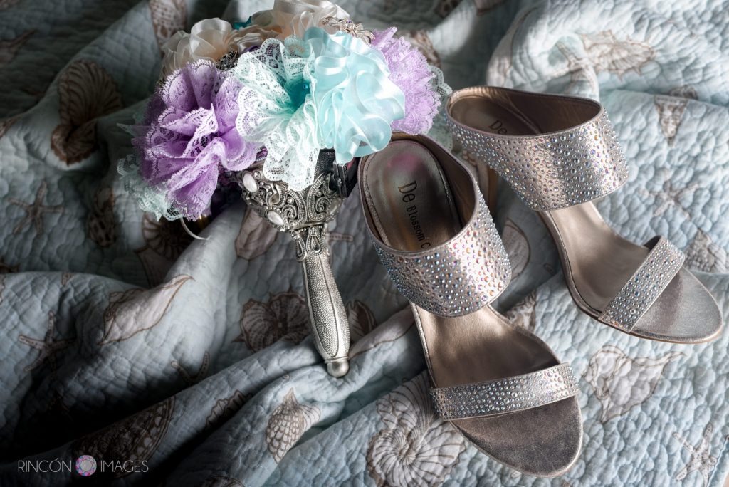 Photograph of the brides handmade purple and teal ribbon bouquet sitting next to her sequin silver wedding shoes.