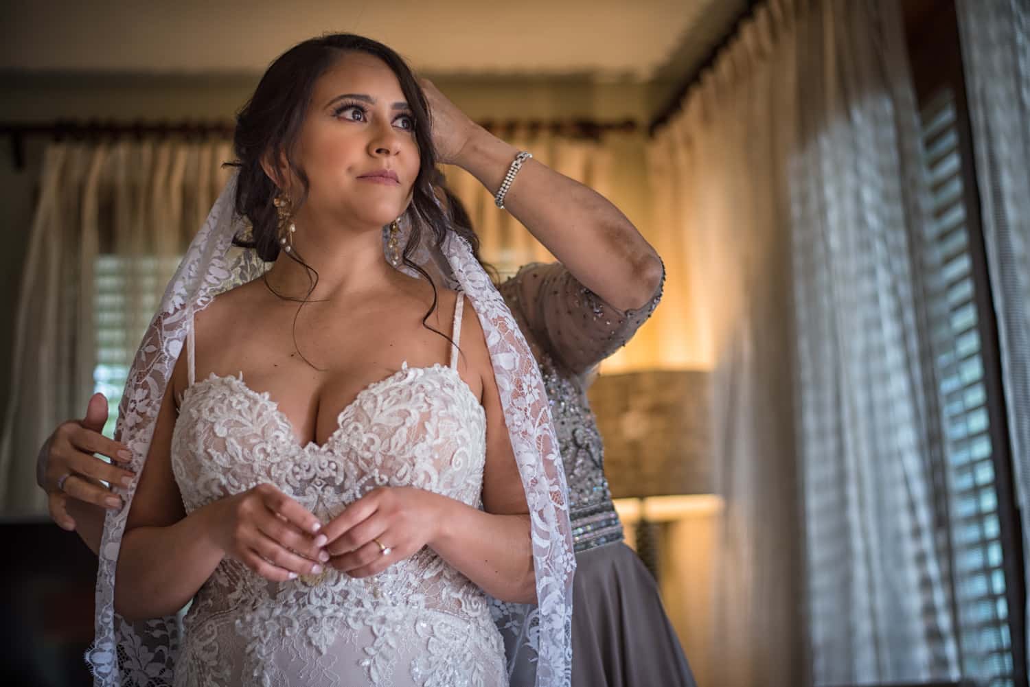 Mother of the bride fixes the brides veil in her hotel room.