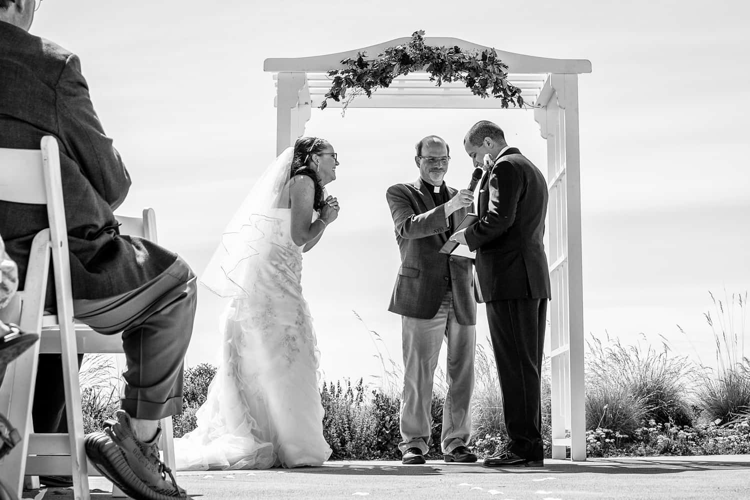 Bride clasping her hands together while the groom reads his vows during their Chambers bay golf club wedding