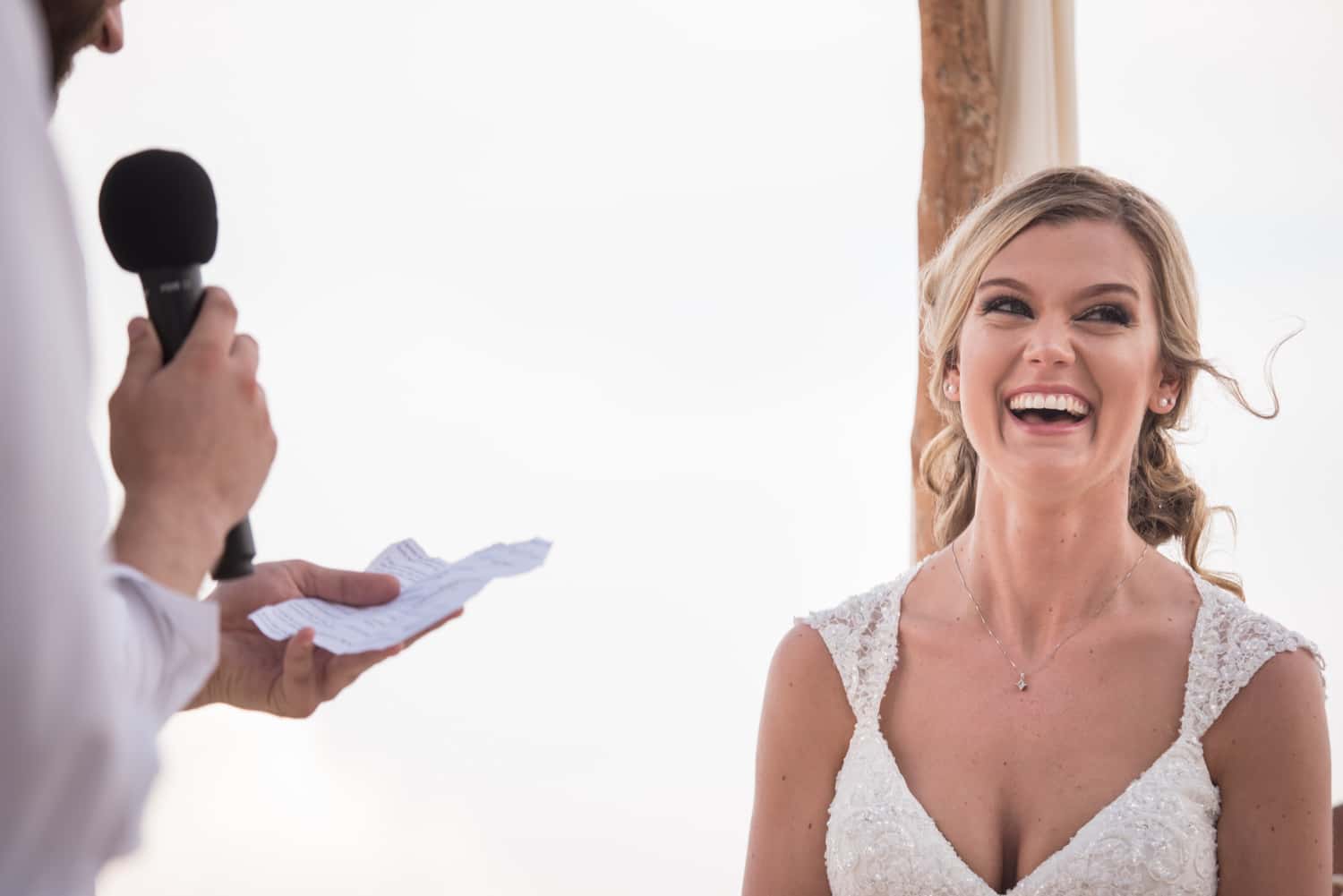 Bride smiling while groom reads vows