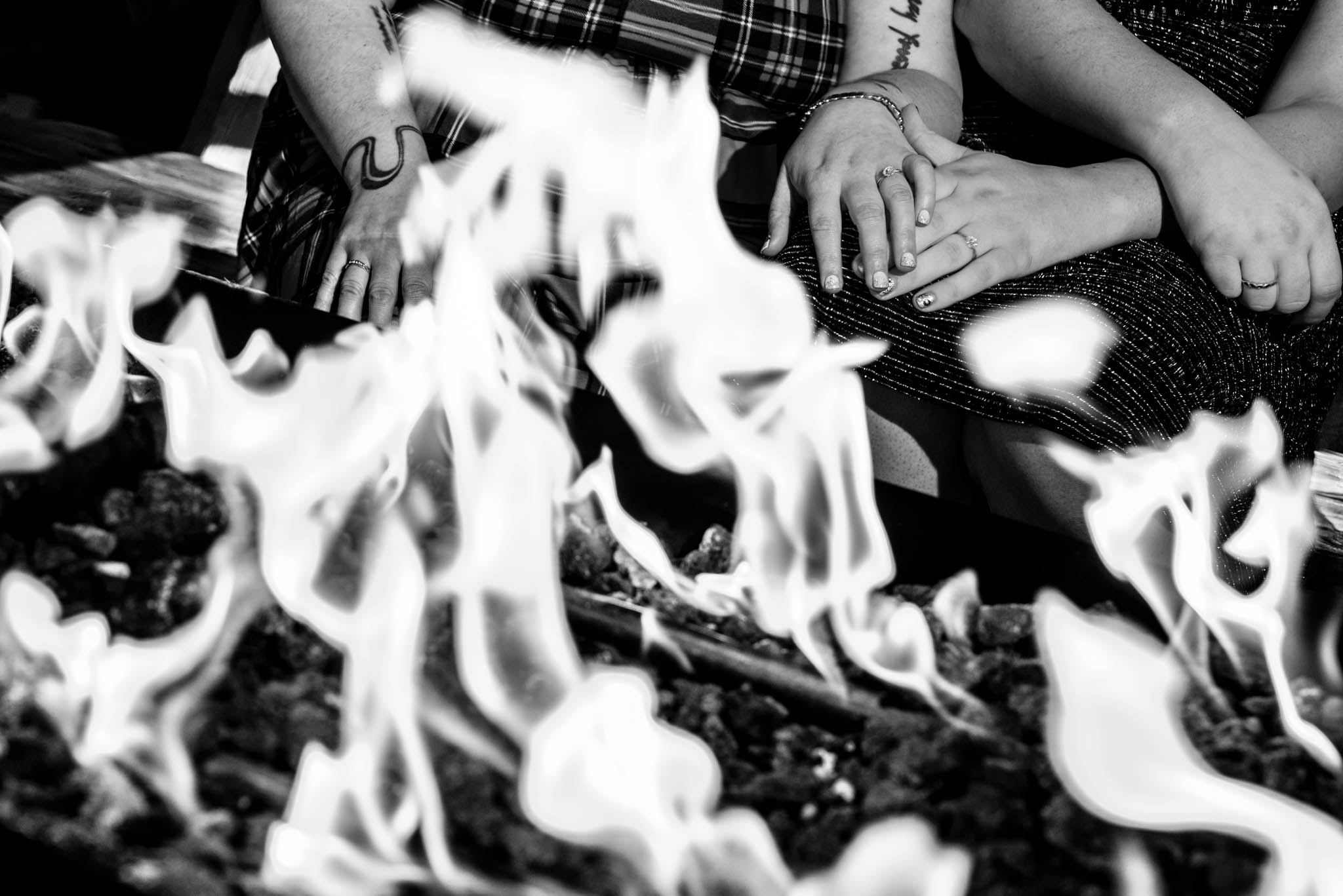 Creative photograph of brides hands with wedding rings in front of the fire