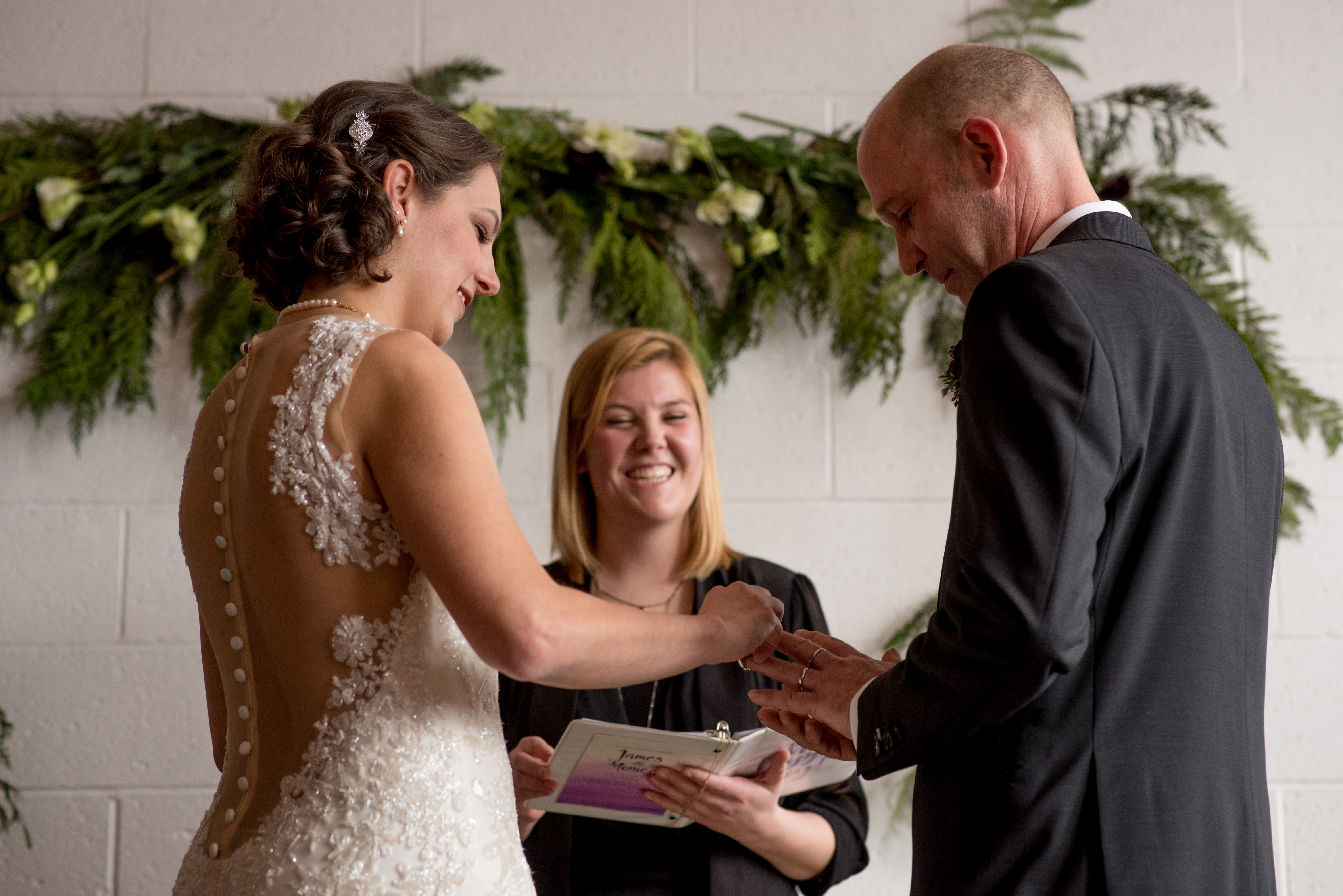 Bride putting the ring onto the grooms finger during their wedding ceremony 