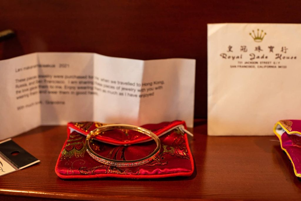 Picture of gold bangle placed on top of a red pouch given from a grandmother to a bride and presented while getting ready at The Astoria Inn.